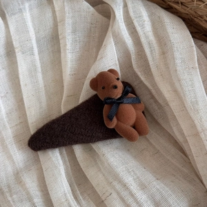 Close-up of brown flocked bear hair clip on soft beige textured fabric background