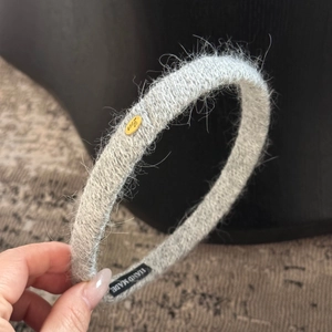 Détail d'un serre-tête en peluche grise avec plaque dorée Love et étiquette faite main