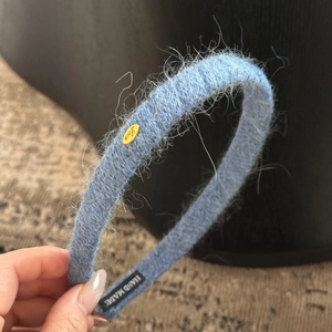 Détail d'un bandeau en maille bleue avec plaque dorée Love et étiquette faite à la main
