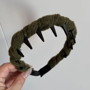 Detail showing the olive green yarn-wrapped band and black anti-slip inner teeth of the headband