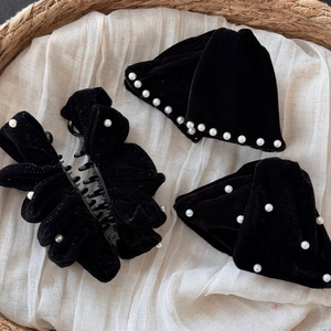 Detail of elegant black velvet hair claw set with white pearls and bow accessories