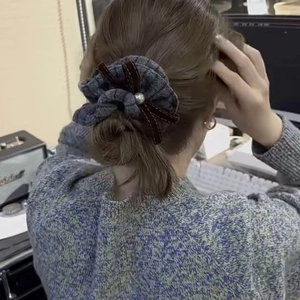 Detailansicht graues Tweed-Haargummi mit Perle und brauner Samtschleife am Haar