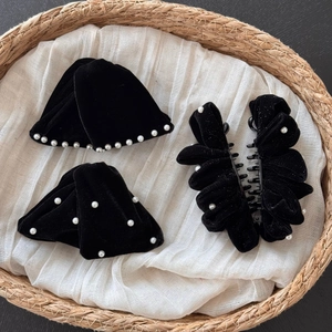Three-piece black velvet hair accessory set with pearls on a straw woven tray