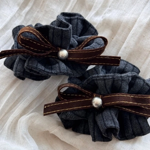Detail von grauen Rippstoff-Scrunchies mit braunen Wildlederschleifen und Perlen