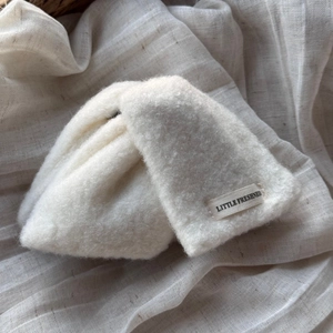 Détail d'une pince à cheveux en peluche blanche avec étiquette Little Freshness sur texture