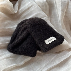 Gros plan sur la pince à cheveux noire en laine montrant la texture douce en peluche