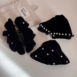Detail of elegant black velvet hair accessories with white pearls on a neutral fabric