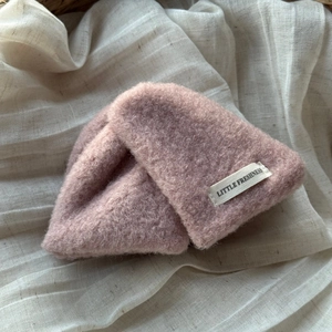 Gros plan du bonnet en tricot rose avec étiquette Little Freshness sur lin beige