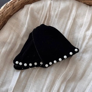 Detail of elegant black velvet hair clips with pearl beads on a rustic linen background