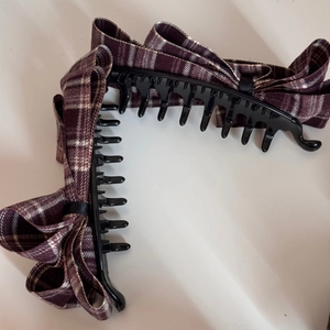 Detailed close-up showing the plaid fabric bow and toothed grip of two red banana hair clips