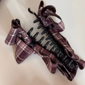 Detail of a black hair clip with a dark purple and white checkered fabric bow