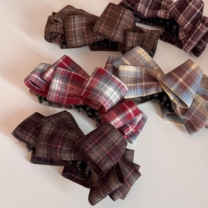 Detail view of various colorful checkered fabric bow hair clips in a stacked arrangement