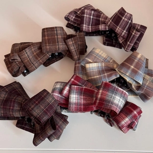 Detail of five vintage plaid fabric bow hair clips in various colors on white background
