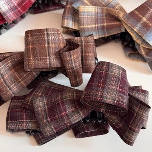 Detailed macro view of multi-layered plaid bow hair clips with textured fabric and claws