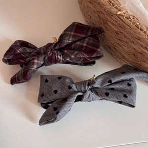 Detail of red plaid and heart pattern fabric bow hair clips with gold metal tags