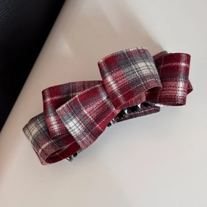 Detail view of the red plaid fabric bow on the black banana clip hair accessory