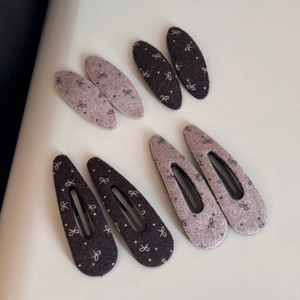 Nahaufnahme von Wollstoff-Haarspangen mit eleganten Bogenmustern in braunen und violetten Tönen