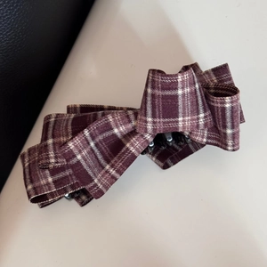 Detailed close-up of a large red plaid bow hair clip with a vintage checkered pattern texture