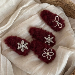 Detail view of four burgundy plush hair clips with sparkling rhinestone floral patterns