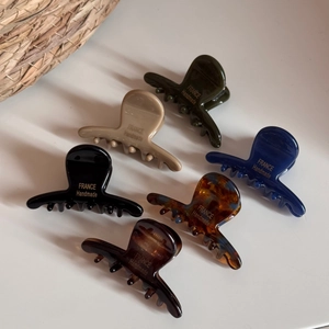 Détail de six pinces à cheveux en acétate colorées avec l'inscription dorée à la main