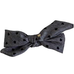 Elegant grey bow hair clip with black hearts and a golden metal accent in high detail