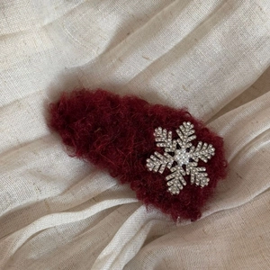 Detail of red plush floral hair clip with silver snowflake and pearl accent