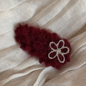 Close-up of deep red plush flower hair clip with silver beads and sparkling rhinestone