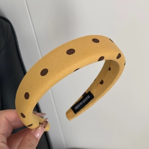 Détail macro du tissu à pois jaunes et de l'étiquette faite main sur le serre-tête rembourré