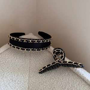 Close-up of black leather chain woven design on headband and hair claw clip accessories
