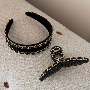 Detail of black leather headband and hair claw clip with golden woven metal chain