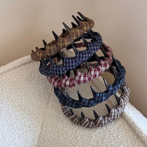 Close-up of assorted British style plaid headbands with teeth on soft white fabric