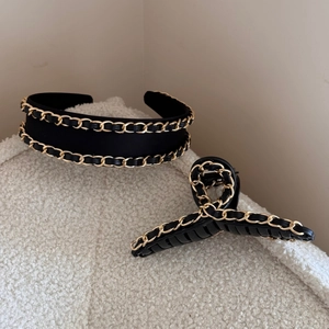 Detail of black leather texture and gold metal chain weave on headband and hair claw clip
