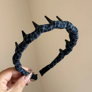 Detail shot of the blue and black plaid headband with black decorative spikes and metal studs
