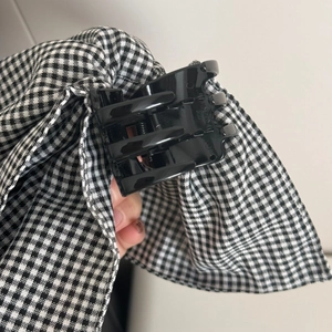 Detailed macro view of black glossy hair claw clip with black and white gingham bow