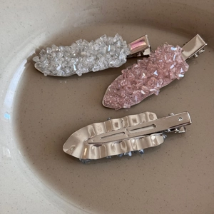 Close-up of three pink and silver crystal duckbill hair clips on a ceramic plate