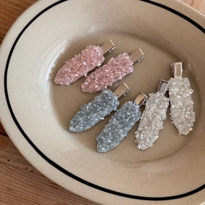 Macro shot of sparkling crystal-encrusted duckbill hair clips in pink, blue, and white colors