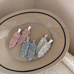 Close-up of sparkling crystal hair clips in pink and blue on a ceramic plate