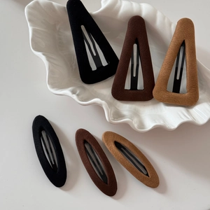 Vue détaillée de la texture velours sur les barrettes triangulaires et ovales aux tons terre