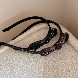 Polka dot leather bow headbands with silver studs in black and brown on white surface
