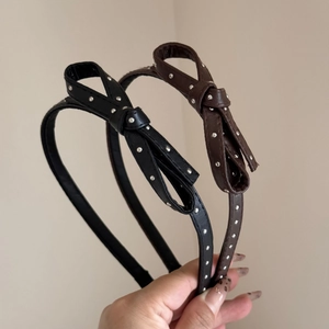 Detail view of black and brown leather headbands with metallic polka dot rivets and bows