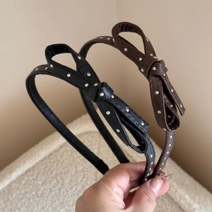 Close-up of black and brown faux leather headbands with silver metal polka dots and bows