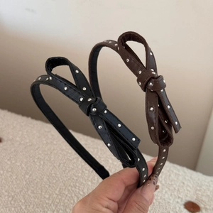 Detail of black and brown faux leather headbands with bow accents and silver studs
