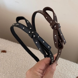 Close-up of leather dot headband with silver metal rivets and sweet bow decoration