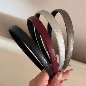Detail of four faux leather headbands featuring snake skin texture in various metallic colors
