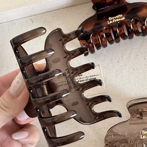 Detailed macro view of resin hair claws featuring gold lettering and strong metal springs