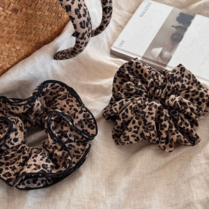 Leopard print hair accessory set with scrunchies and headband on a beige linen fabric