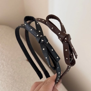 Close-up of bow headbands with silver metal studs in black and dark brown faux leather