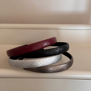 Detailed view of snake skin texture headbands in burgundy, black, silver, and bronze colors