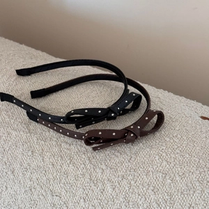 Detail view of black and brown leather headbands with silver studs and side bows