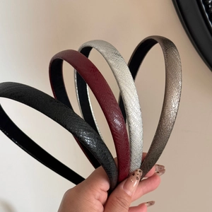 Close-up of slim leather headbands with metallic snake texture in four distinct colors